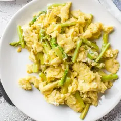 Puszysta jajecznica ze szparagami, podana na białym talerzu. Idealne śniadanie pełne wiosennych smaków.