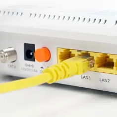 Żółty kabel sieciowy podłączony do portu LAN3 routera. Widoczne też złącze CATV i gniazdo zasilania.