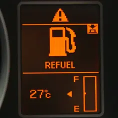 Na desce rozdzielczej świeci się kontrolka paliwa z napisem "REFUEL". Wskaźnik pokazuje niski poziom paliwa, co oznacza, że niedługo trzeba będzie tankować. Zastanawiasz się, ile km na rezerwie jeszcze przejedziesz.