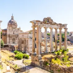 Rzym last minute: ruiny Forum Romanum z kolumnami i łukiem Triumfalnym, w tle kopuła kościoła.