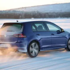 Niebieski Golf 4 4motion z napędem na cztery koła śmiga po ośnieżonej drodze, unosząc śnieg spod kół.