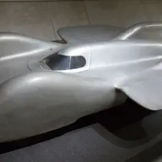 Srebrny, opływowy Mercedes T80, legendarny samochód wyścigowy, prezentuje swoje aerodynamiczne kształty.