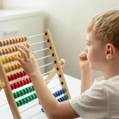 Chłopiec z blond włosami uczy się liczyć na liczydle, pokonując trudności związane z dysleksją matematyczną.