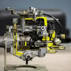 Przekrój pompy wtryskowej diesla. Widoczne elementy mechaniczne i żółte kanały paliwowe. Uszkodzona pompa paliwa diesel objawy mogą być różne, od nierównej pracy silnika po jego całkowite unieruchomienie.