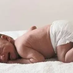 Noworodek w pieluszce leży na białym tle. Obraz symbolizuje nadzieję na pokonanie neuroblastoma.
