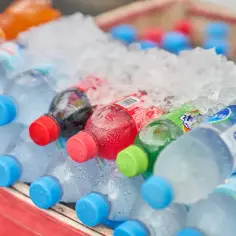 Butelki z napojami, w tym Fanta, schłodzone w lodzie. Czy woda ma kalorie? Czysta woda nie, ale te słodkie napoje już tak.