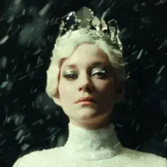 Marion Cotillard w koronie i błyszczącej sukni, otoczona śniegiem, jak z jej filmów.