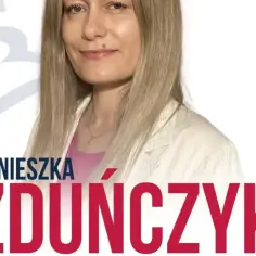 Agnieszka Zduńczyk, uśmiechnięta blondynka w jasnej marynarce, z dużym napisem jej nazwiska.