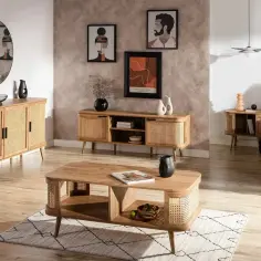 Jak zagospodarować róg pokoju salon? Drewniane meble z rattanowymi frontami, okrągłe lustro i grafiki na ścianie tworzą przytulną przestrzeń.