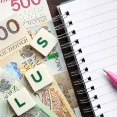 Polskie banknoty, litery P, L, U, S, notatnik i różowy długopis.