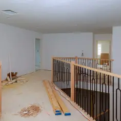 Nowe balustrady z drewnianymi słupkami i czarnymi metalowymi prętami czekają na mocowanie balustrady do ściany. Wnętrze w trakcie remontu.