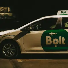 Biały samochód z zielonym logo Bolt na drzwiach i na dachu. To auto do pracy w Bolt.