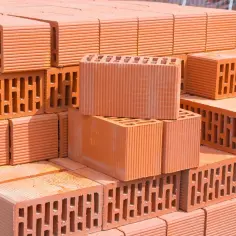 Stos pustaków ceramicznych, idealnych do budowy ścian. Wybór między pustakiem ceramicznym a gazobetonem zależy od potrzeb.