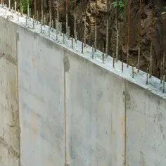 Gotowy do dalszych prac mur oporowy prefabrykowany, z wystającymi prętami zbrojeniowymi, czeka na betonowanie.