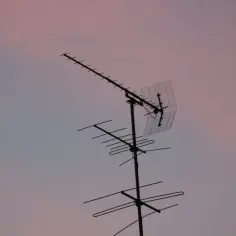 Antena telewizyjna na tle różowego nieba. Dowiedz się, jak podłączyć kabel antenowy do anteny, aby cieszyć się najlepszym odbiorem.