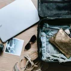 Pakowanie na wyjazd: laptop, aparat, okulary, sandały i kosmetyki w bagażu rejestrowanym.