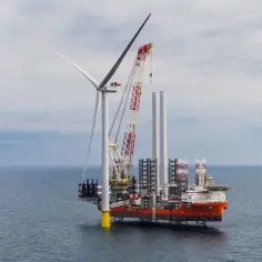 Budowa farmy wiatrowej na Bałtyku. Statek z dźwigiem montuje turbinę wiatrową.