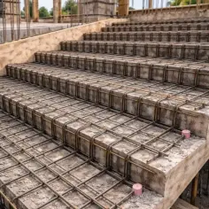 Schody dywanowe betonowe w budowie, z widocznym zbrojeniem stalowym.