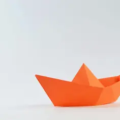 Pomarańczowy stateczek z papieru, idealny do zabawy i nauki origami dla dzieci. Gotowy do wypłynięcia na przygodę!