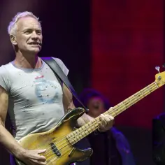 Sting gra na gitarze basowej, a obok niego muzyk gra na harmonijce. Koncertowy sting dzieci.