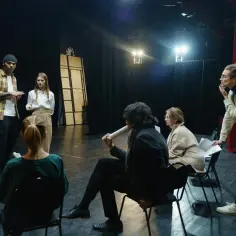 Aktorzy na scenie przygotowują się do spektaklu, omawiając tekst.
