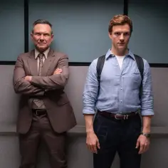 Dwóch mężczyzn w garniturach, jeden z nich to młody Dexter, który odkrywa swój **dexter original sin**.