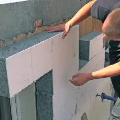Budowlaniec montuje płyty styropianowe do ocieplenia domu. Wybór odpowiedniego styropianu to klucz do energooszczędności.