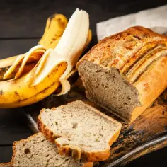 Pyszne, wilgotne ciasto bananowe, które zawsze się udaje. Obok leżą dojrzałe banany, idealne do wypieków.