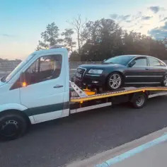 Laweta z ciemnym Audi na pokładzie jedzie po autostradzie. Zastanawiasz się, ile wazy laweta z takim ładunkiem?