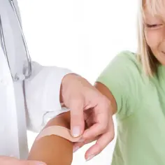 Pielęgniarka zakłada plaster dziecku. Zastanawiasz się, ile zarabia pielęgniarka szkolna?