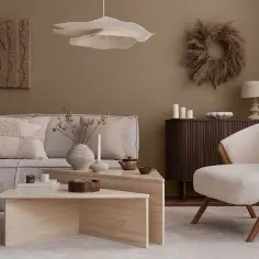 Salon w stylu japandi: beżowa sofa, puszysty fotel, kamienne stoliki i dekoracje z traw.