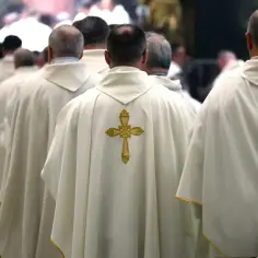 Księża w białych szatach z krzyżami idą w procesji. Czy wdowiec może zostać księdzem? Tak, w niektórych obrządkach.