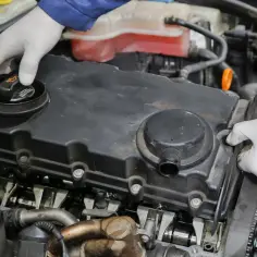Mechanik w białych rękawiczkach sprawdza silnik. Może to być związane z nieszczelna odma objawy.