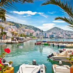 Malowniczy port w Albanii, z górami w tle. Zastanawiasz się, ile trwa lot do Albanii z Poznania?
