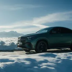 Zielony Mercedes GLE 450d na tle ośnieżonych gór i krzyża.