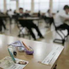 Na stole leży legitymacja szkolna, ołówek i przybory. W tle uczniowie siedzą w ławkach. Czy można sprzedać alkohol na legitymacje?