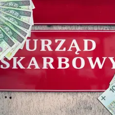 Ulga dla pracujących seniorów? Na czerwonej tablicy "URZĄD SKARBOWY" leżą polskie stuzłotówki.