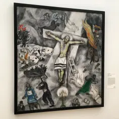 Obraz Chagalla przedstawia ukrzyżowanego Chrystusa pośród chaosu wojny, z płonącymi budynkami i żołnierzami.