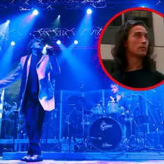 Koncert Lady Pank. Wokalista na scenie, w tle perkusista i fragment twarzy muzyka w okręgu.