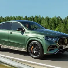 Zielony Mercedes GLE AMG pędzi po drodze, otoczony lasem.