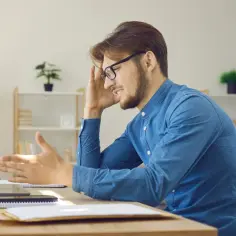 Frustracja mężczyzny przy biurku. System Windows zatrzymał to urządzenie z powodu zaraportowanych problemów (kod 43).