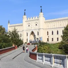 Zamek Lubelski z dwoma turystami idącymi po moście.