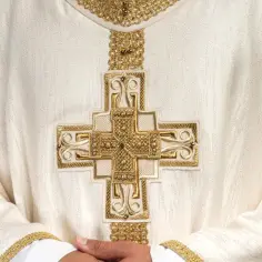Biała szata z haftowanym złotym krzyżem. Szukasz miejsca, gdzie kupić krzyż do domu?