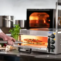 Szef kuchni wyjmuje pizzę z rozgrzanego piekarnika. Dowiedz się, jak ustawić piekarnik na pizzę, by uzyskać idealny efekt.