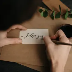 Piszę list do dziewczyny. Na białej etykiecie piórem z kałamarza tworzę napis "I love you".