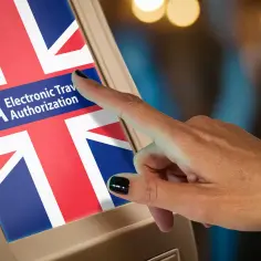 Dłoń dotyka ekranu z flagą Wielkiej Brytanii i napisem ETA. Czy potrzebna wiza do Anglii? ETA to elektroniczne zezwolenie na podróż.