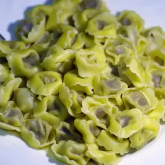Porcja świeżo ugotowanego makaronu tortellini na białym talerzu. Zastanawiasz się, ile gotuje się makaron? Te wyglądają idealnie!