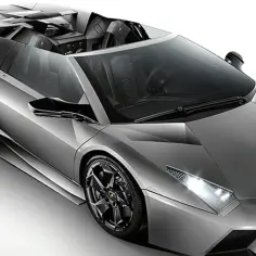 Srebrny, otwarty Lamborghini Reventon z czarnymi felgami i sportowym wnętrzem.