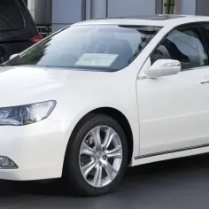 Biały Honda Legend z chromowanymi detalami i felgami, zaparkowany obok czarnego SUV-a.