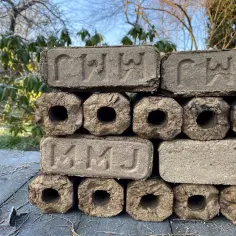 Stos brykietu drzewnego na drewnianym stole, z widokiem na ogród.